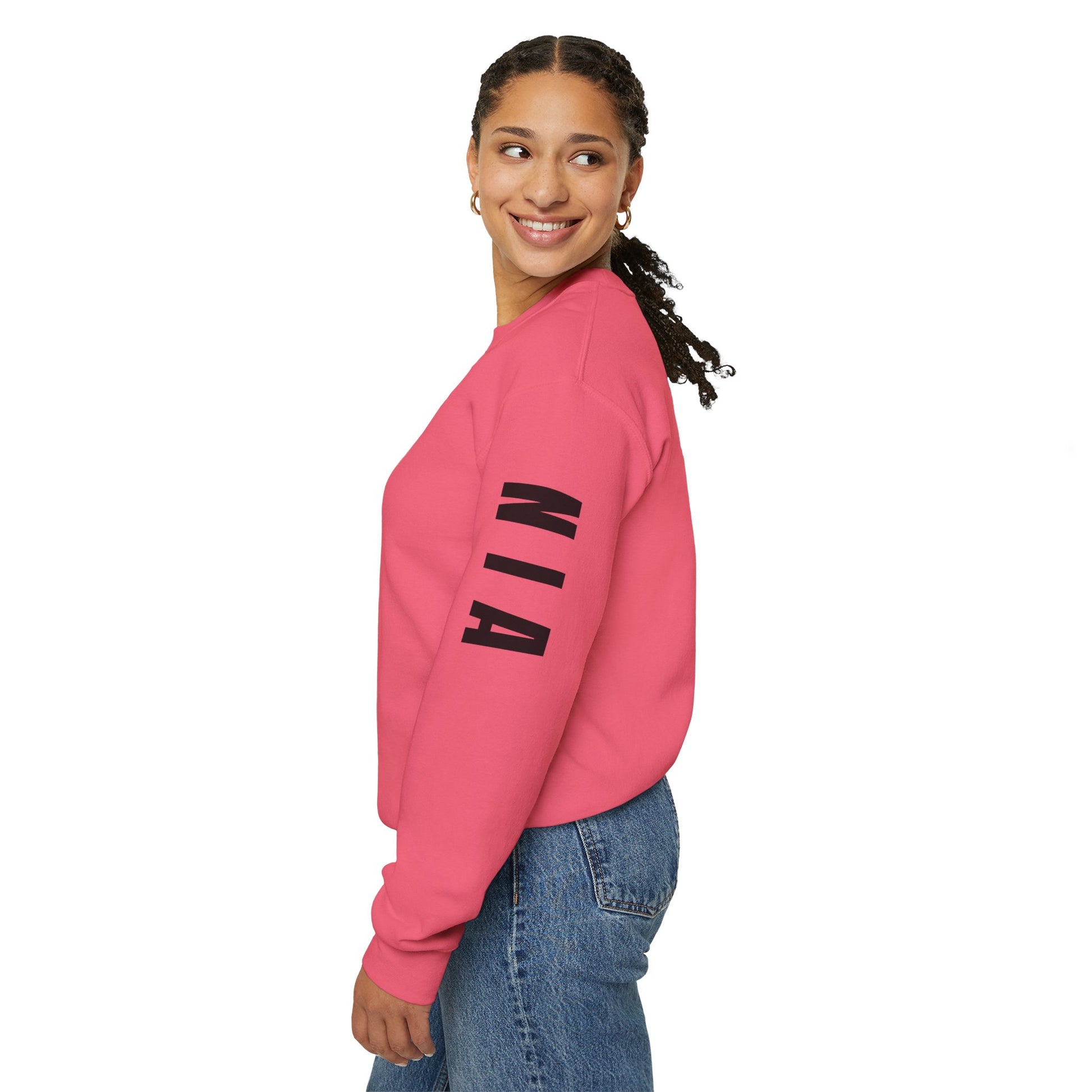 Person wearing a pink sweatshirt with 'NIA' printed on the sleeve against a white background