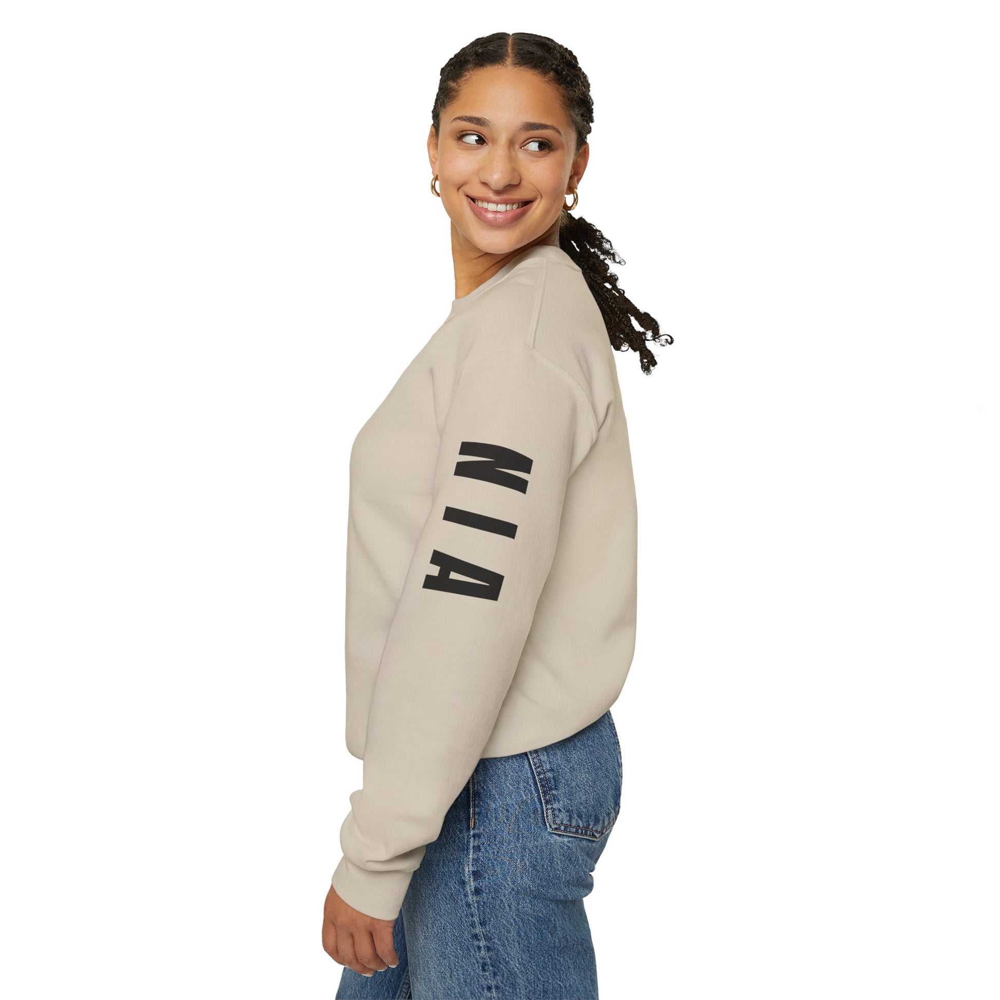 Woman wearing a beige sweatshirt with 'NIA' text, standing against a white background
